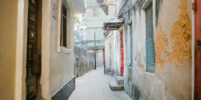 Paved narrow street between aged stone residential houses with shabby facade in city