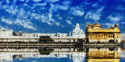 The Golden Temple, Harmandir Sahib, in Amritsar beautifully reflected in water with a vivid blue sky.