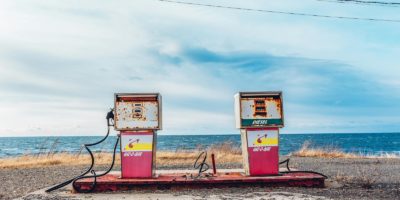 Vintage gas pumps on a deserted seashore with a clear sky and ocean view.