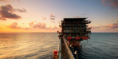 A breathtaking view of an oil platform on the ocean at sunset, showcasing industrial beauty.