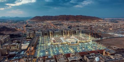 A stunning aerial view of Al-Masjid an-Nabawi in Medina at dusk, showcasing its illuminated grandeur.