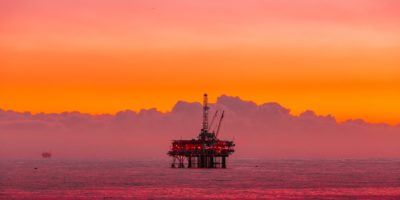 an oil rig in the middle of the ocean at sunset